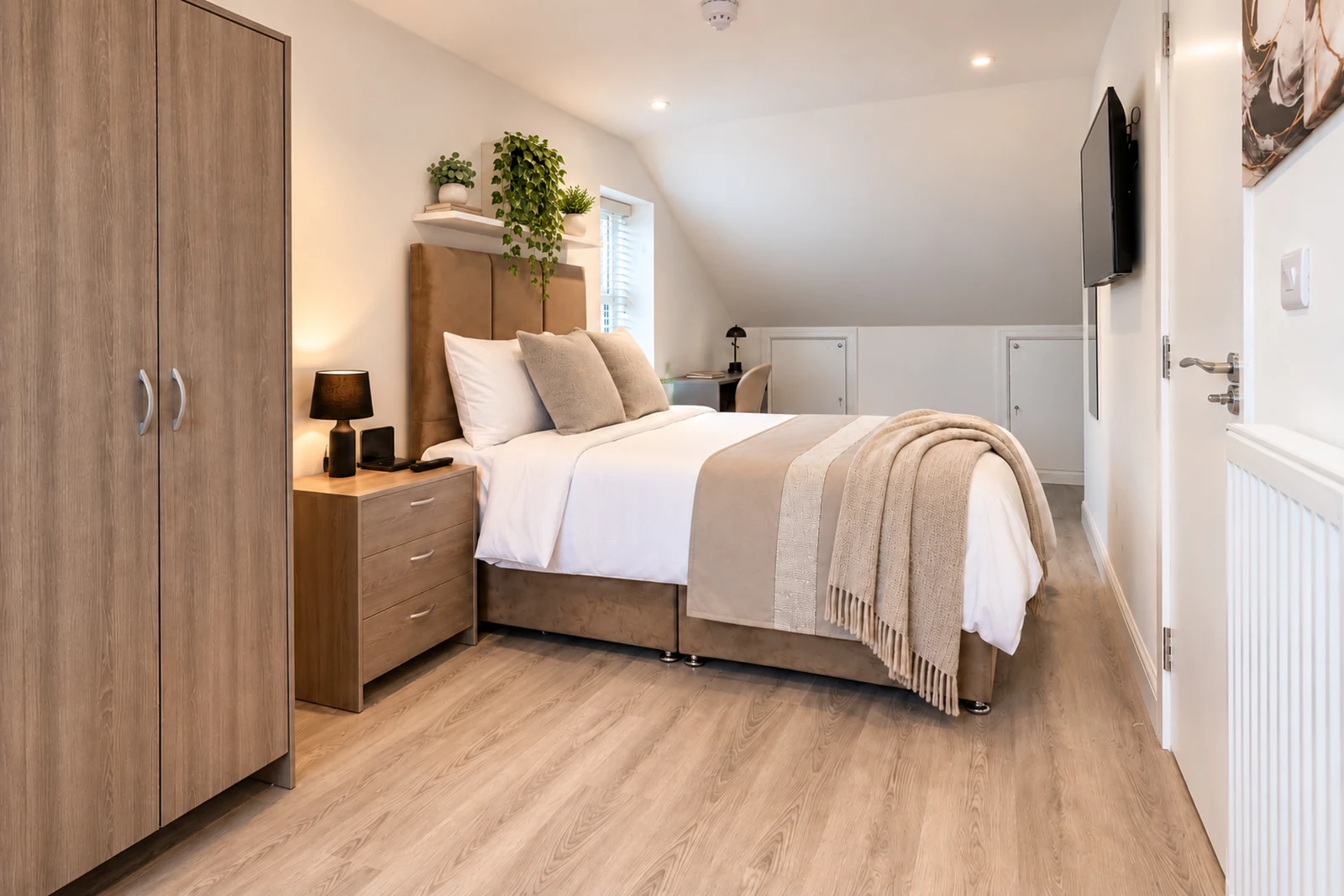 Room 5’s loft layout, with a bed, wardrobe, workspace and wall-mounted smart TV.