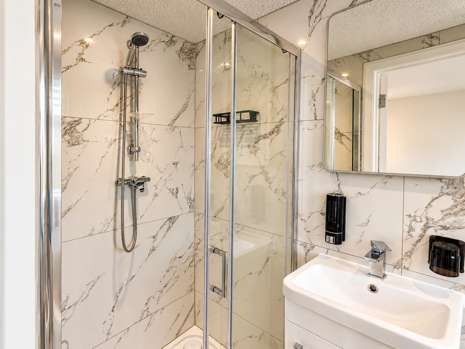 Room 5’s private en-suite shower, with a basin and mirror.