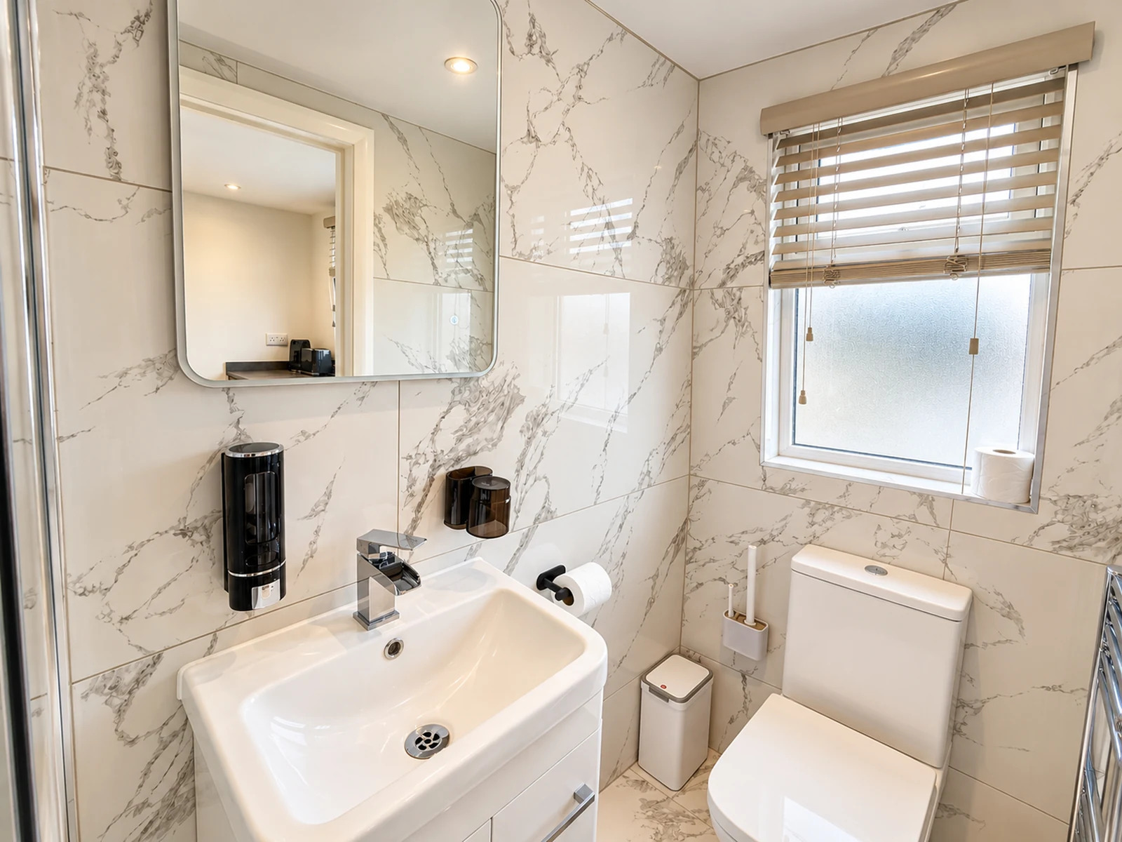 Room 5’s private bathroom, with a basin, toilet and frosted window.